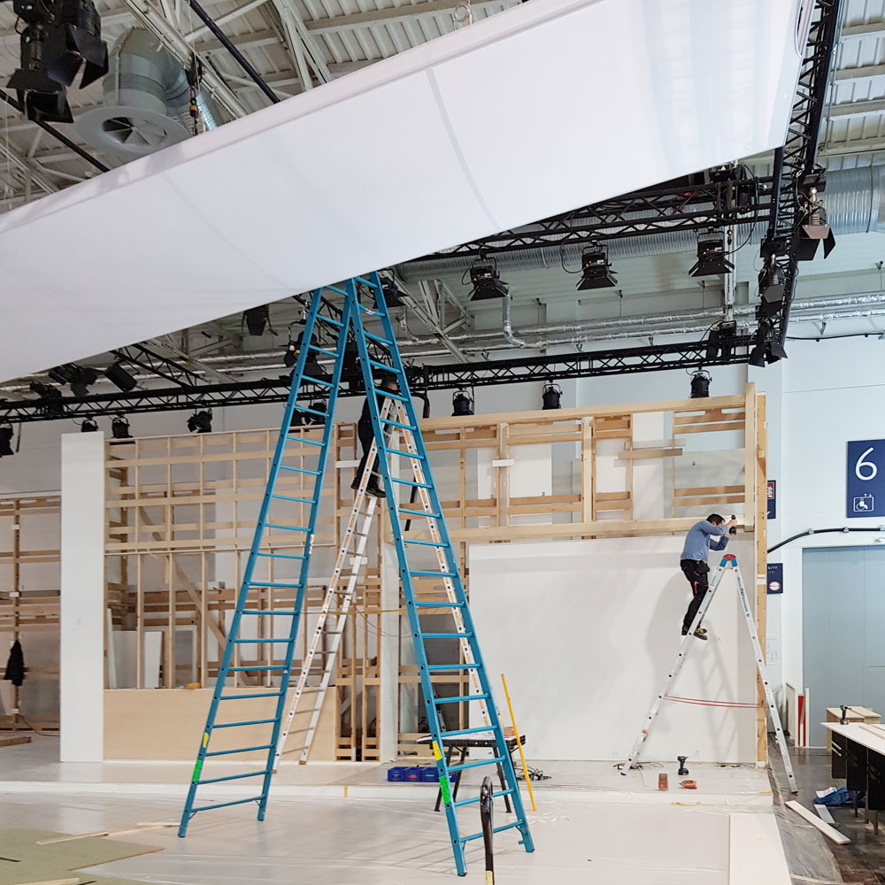 tuennissen-leistungen-aufbau Aufbau der Standarchitektur in einer Messehale mit Monteuren auf Leitern - Tünnissen Interiors, Messen, Events und Ausstellungen NRW Deutschland Europe